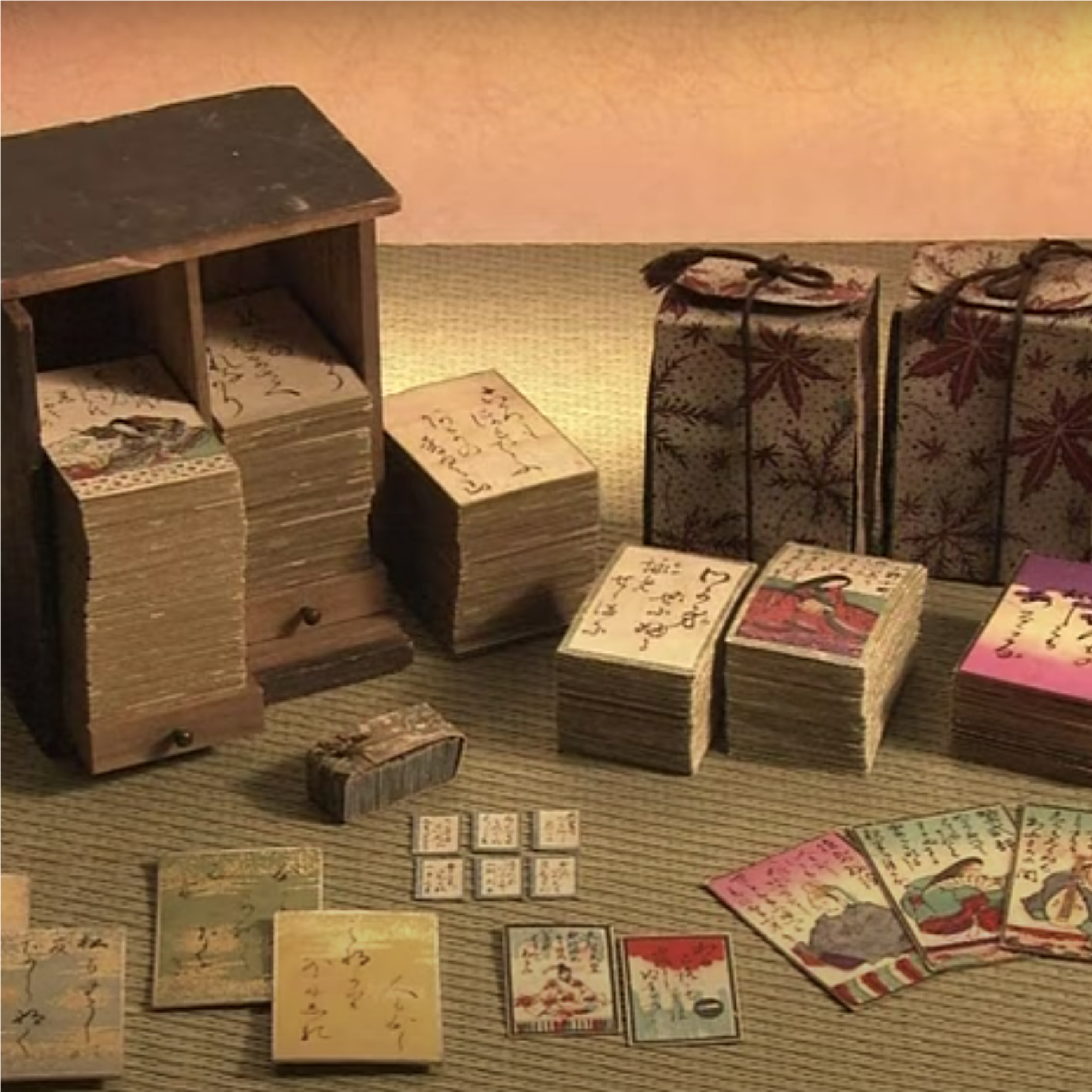 En la imagen se ven cartas tradicionales del juego japonés karuta desplegadas en pilas sobre un tatami. Fueron realizadas sobre papel artesanal e impresos con stencil a color. Algunas pilas de cartas se encuentran dentro de su caja de madera.